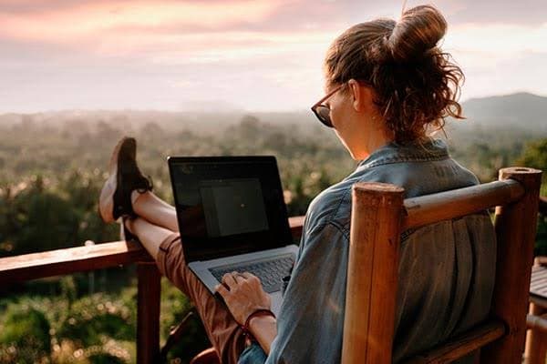 Una persona trabaja con su laptop en un chiringuito frente al mar
