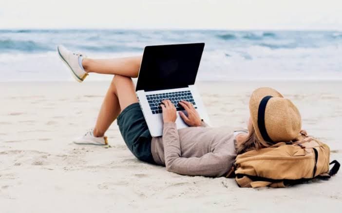 Una mujer trabaja con su laptop en un mirador sobre la selva, al atardecer