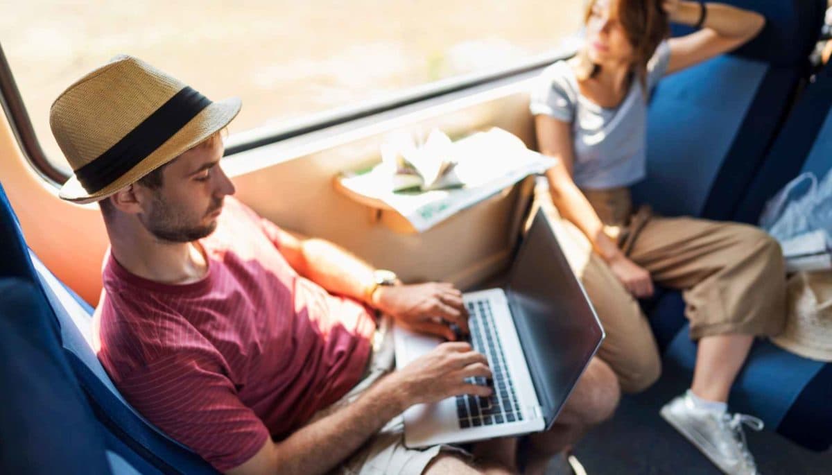 Dos personas trabajan con su laptop en un tren en marcha